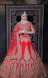 Beautiful Indian bride wearing a red embroidered lehenga with intricate jewelry, showcasing traditional elegance.
