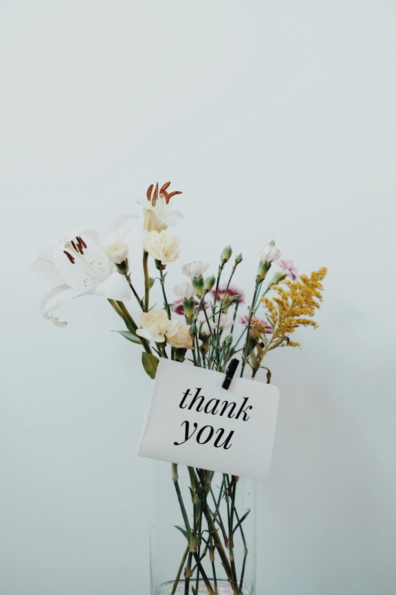 Delicate bouquet featuring a thank you note on a soft white background.